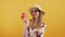 Medium studio shot on an orange background of an elegant young caucasian blonde woman holding a red apple, wearing a