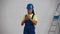 Medium video of a dark-skinned young female construction worker standing in the room, holding a smartphone, waiting for