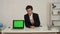 Medium video of a young man in an office, with a laptop that has an advertising area, workspace mock up on it. The man