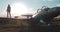 Medium view of tourist girl walking along wing of broken Soviet combat fighter plane, then turning around and throwing