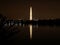 Medium wide shot of the Washington Monument with night lights of Washington, D.C.