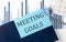 MEETING GOALS on sticky note on notebook on the chart background