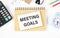 MEETING GOALS. TEXT ON WHITE PAPER.