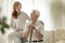 Meeting of smiling granddaughter with happy grandfather with walking stick at home