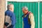 Meeting of two mature neighbors at the gate of a rural house on a sunny day