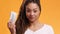 Mega profit. Confident young african american woman playing with stack of dollar banknotes, orange studio background