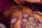 Mehendi artist paints an ornament of henna on an eastern beautiful girlâ€™s stomach