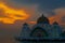 Melaka Straits Mosque at sunset by the water with orange blue gr