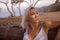 Melancholic portrait of young attractive and beautiful blond woman leaning her face relaxed on trunk at Autumn forest or park