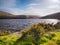 Meldon Reservoir on West Okement River with yellow gorse and sun reflecting on water Dartmoor National Park, Devon