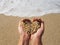 Mellow heart shaping female hands above sea and beach