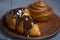 Melted black or milk chocolate pours onto a croissant or cinnamon roll