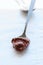 Melted chocolate paste in a spoon on a whte stone background. Cl