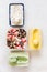 Melted ice cream in individual containers featuring chocolate , vanilla bean , fruit and matcha mint ice cream on white background