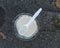 Melted Vanilla Ice Cream Cup and Spoon on Asphalt