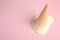 Melted vanilla ice cream in wafer cone on pink background, above view