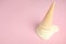 Melted  vanilla ice cream in wafer cone on pink background. Space