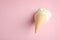 Melted vanilla ice cream in wafer cone on pink background. Space for text