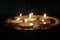 Melted wax tealight candles or diya lamps glowing in dark night. candles arranged in rows in darkness.