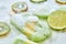 Melting green ice cream on a stick with pieces of peach on a gray background with pieces of ice, kiwi, lime and kiwi