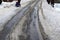 melting layer of snow on road creates deep ruts through which the