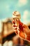 Melting vanilla ice cream cone on hand against blue sky and Brooklyn bridge in the background