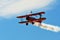 Memorial Airshow. Red Stearman biplane flying towards camera while trailing smoke in exhibition