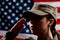 Memorial day. A portrait of female soldier in uniform salutes against the background of the American flag. Side view. The concept