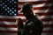 Memorial day, veterans day. Portrait of a Soldier holding a rosary and praying. American flag on the background. Dark colors.