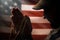 Memorial day, veterans day. A soldier holds a rosary in his hands and prays holding it to his face. Close up. American flag on the