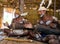 Men Asmat tribe are sitting at home and play on the drum.