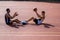 Men basketball players sitting together on court throwing ball to each other.