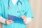 A men in a bright turquoise medical uniform makes entries in the patient`s medical record. Close-up, cropped paramedic.