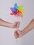 Men couple with hairy hands holding rainbow color windmill toy on a gray background