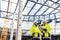 Men engineers standing outdoors on construction site, using tablet.