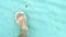 Men feet walking under turquoise sea water. man foot step on ripple white sand.