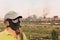 Men in gas mask and cap on industrial factory and smoking pipe b