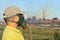 Men in gas mask and cap on industrial smoking pipe background.