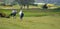 Men on golf course walking towards Pin with golf bags.