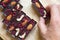 Men hand take healthy homemade chocolate sticks with almonds, cashews and raspberries, lie on a round kitchen board on a