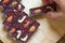 Men hand take healthy homemade chocolate sticks with almonds, cashews and raspberries, lie on a round kitchen board on a