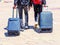 Men have backpacks on their backs. Two men walk with suitcases on wheels. Blurred image