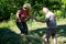 A men helping a woman to step on the ground. Putting the grass on the trailor. Farm chores, working on a field.