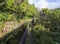 Men hiker walking on footpath along Lavada - water irrigation canals covered by moss and lush vegetation on hiking trail