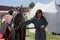 Men in medieval clothes prepares a horse for jousting