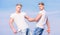 Men muscular twins brothers in white shirts sky background. Brotherhood concept. Benefits and drawbacks of having