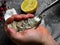 Men opening raw oyster with knife, closeup. The persons hands shucking fresh oysters