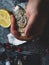 Men opening raw oyster with knife, closeup. The persons hands shucking fresh oysters