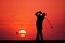 Men play golf at sunset