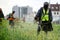 Men in protective suits mow the grass on a city lawn with manual diesel lawn mowers. Improvement and economy of a urban